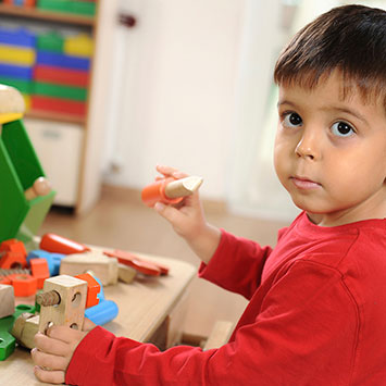 Young boy using wooden play tools to build