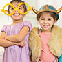 Young girl wearing yellow oversized glasses and another wearing a viking hatYoung girl wearing yellow oversized glasses and another wearing a viking hat and vest
